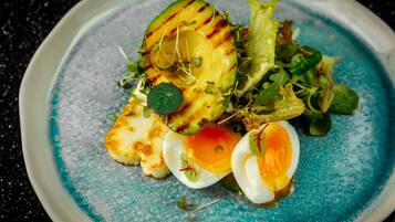 A plate with grilled vegetables, greens, and a halved boiled egg.
