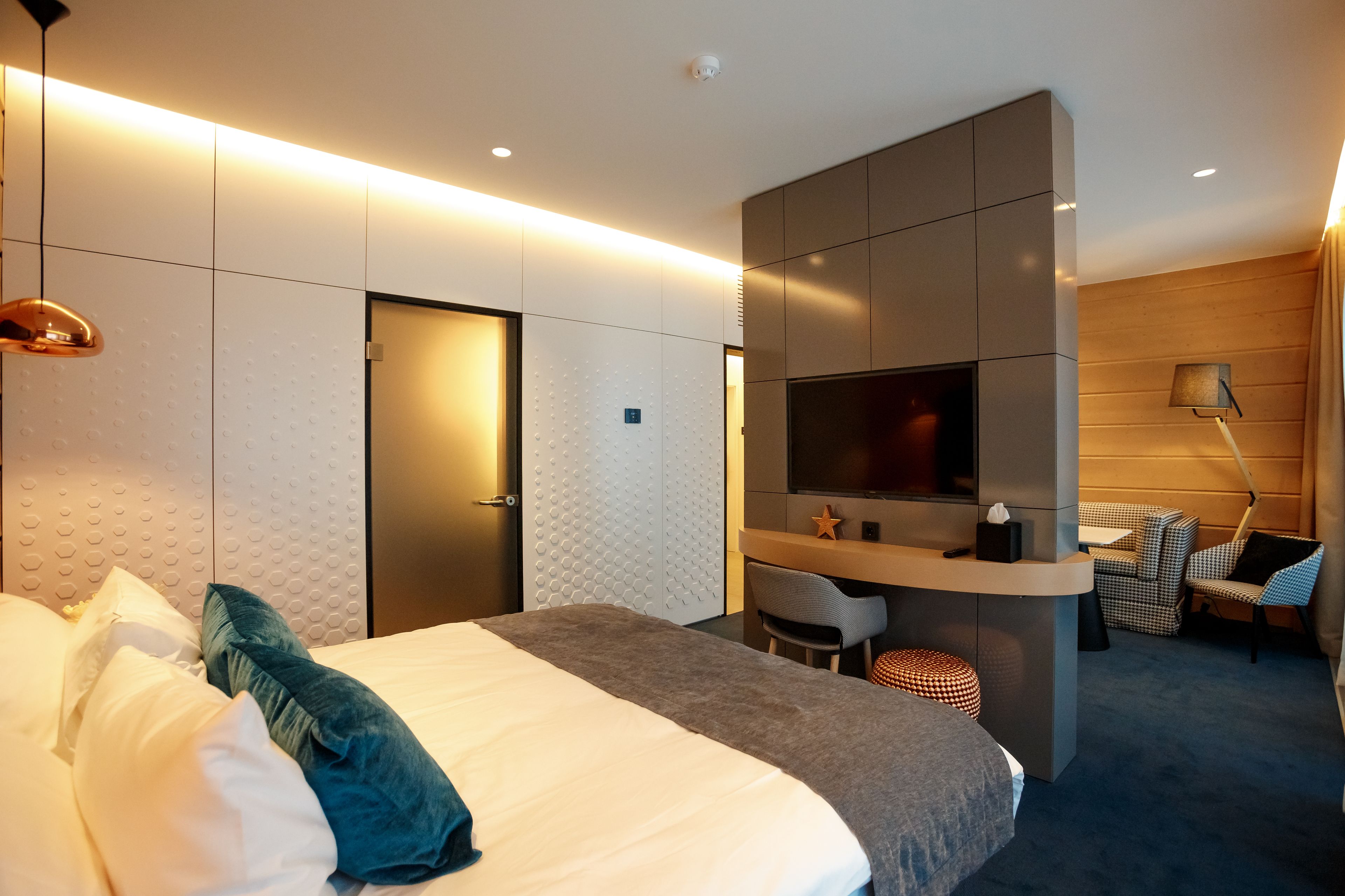 Een moderne hotelkamer met een groot bed, een bureau, een televisie en een zithoek met stoelen.
