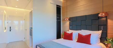 Un dormitorio moderno con una cama grande, un cabecero de madera y una almohada decorativa roja.