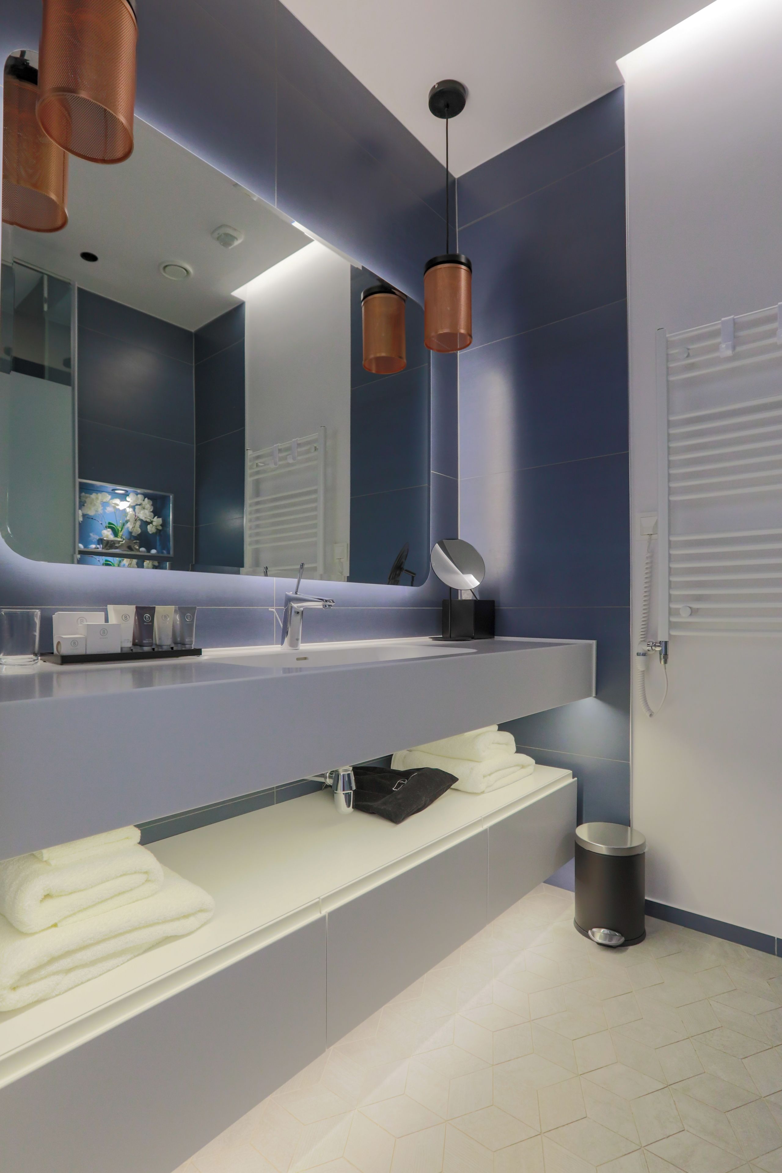A modern bathroom with a large mirror, a sink, and a towel rack.