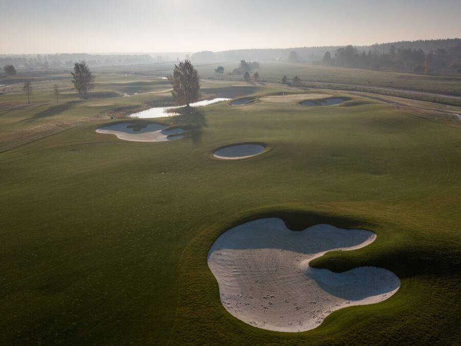 En golfbana med flera sandbunkrar och ett vattenhinder.
