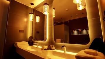 A modern bathroom with two sinks, a large mirror, and pendant lights.