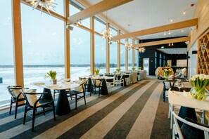 A modern restaurant with large windows, striped carpet, and tables set for dining. - Jurmala Golf Club & Hotel (Marupe Municipality)