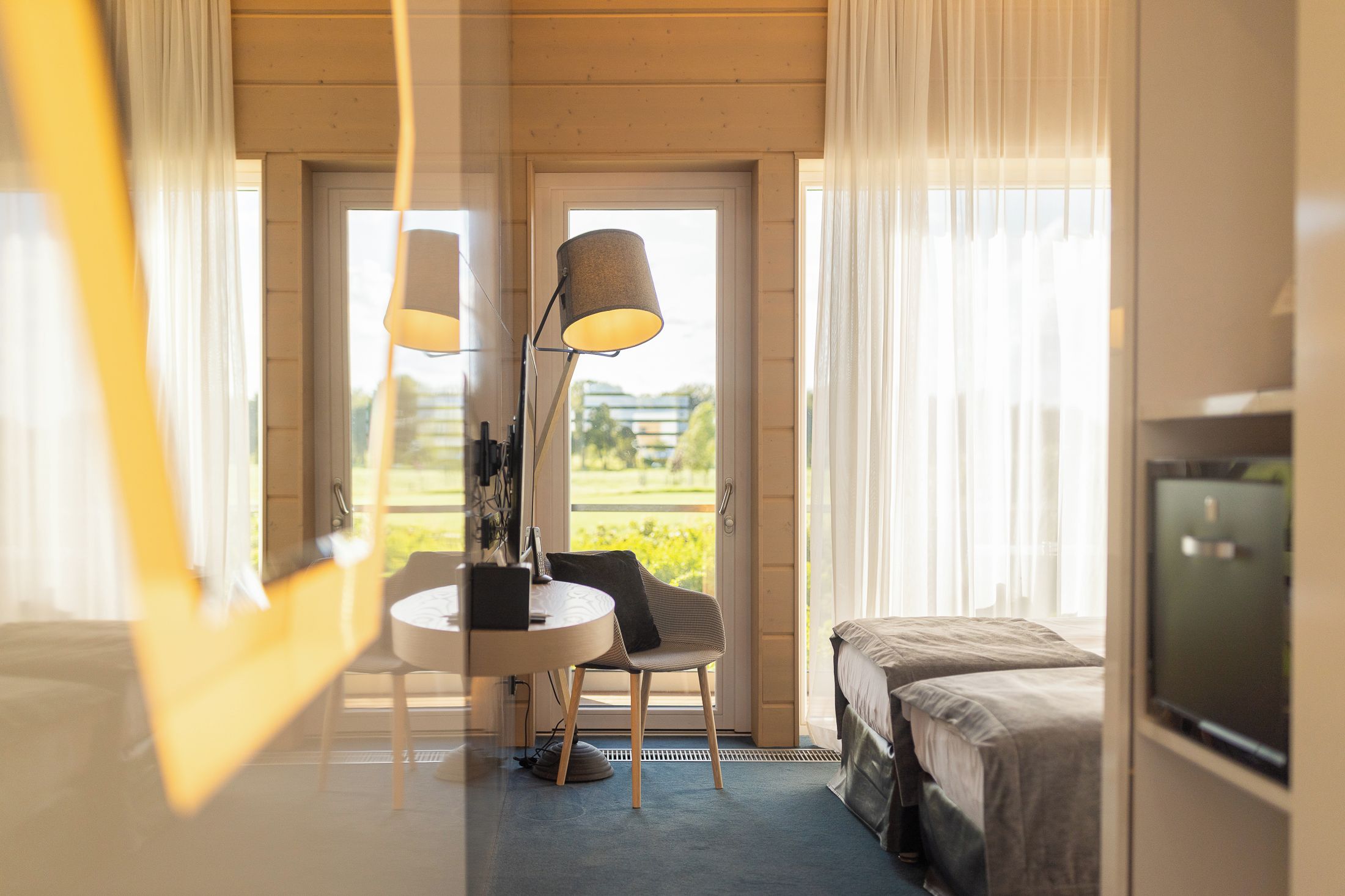Ett hotellrum med en säng, ett skrivbord med en stol, en lampa och en tv.