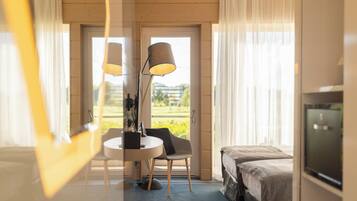 Ett hotellrum med en säng, ett skrivbord med en stol, en lampa och en tv.