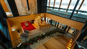 Een moderne hotel lobby met een centrale zithoek, een trap en uitzicht op het omliggende landschap.