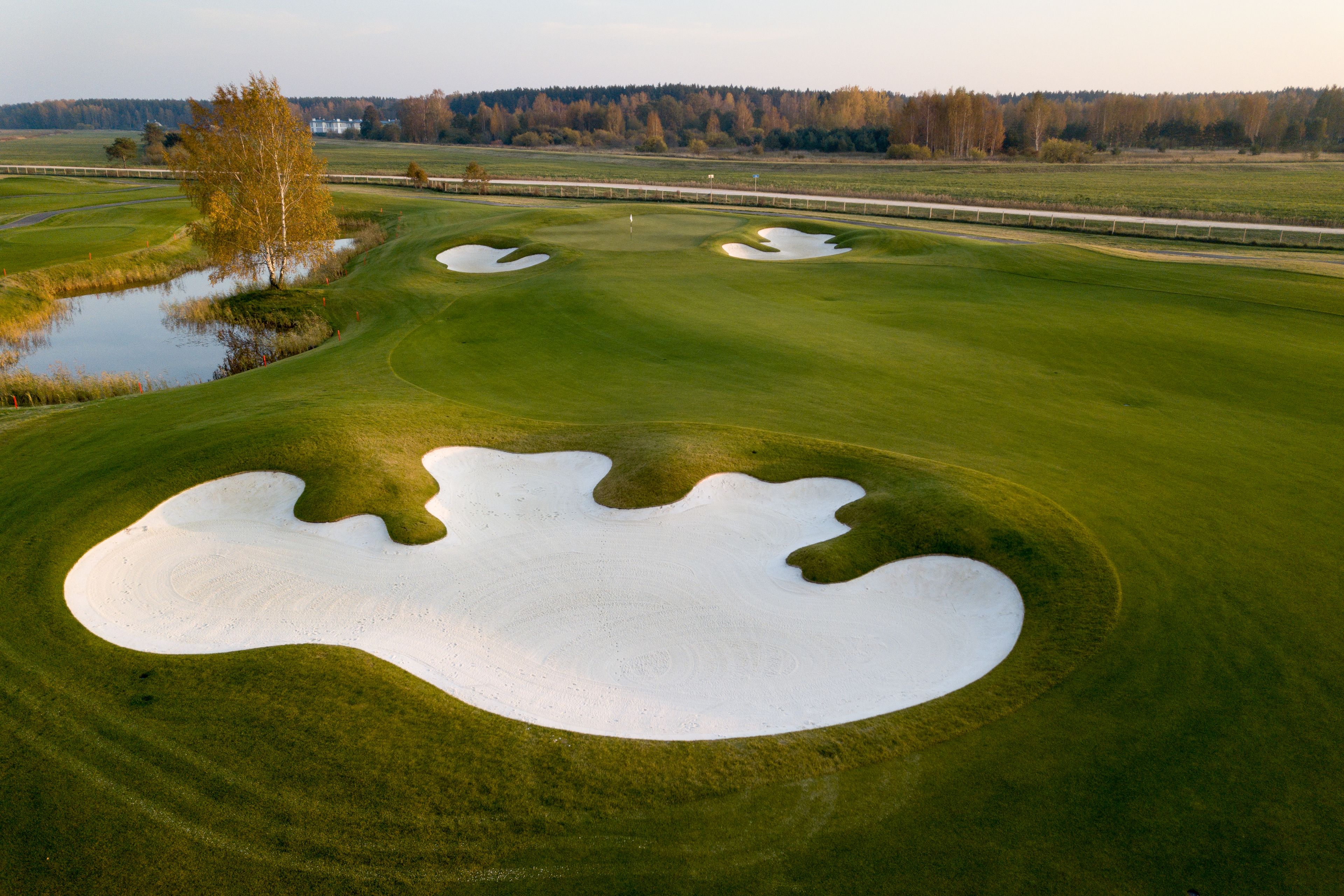 Un parcours de golf avec des bunkers de sable et un obstacle d’eau.
