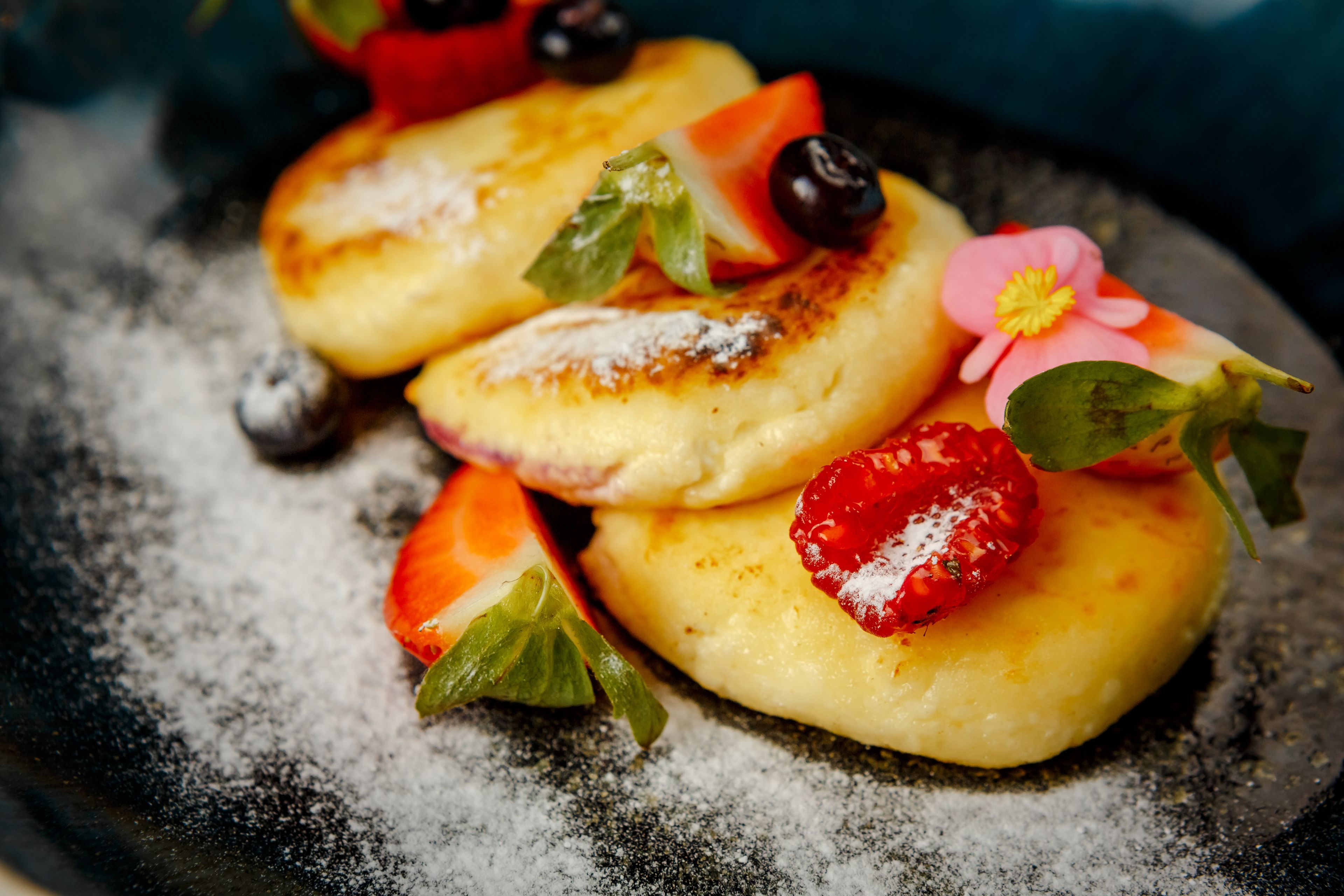 Tres tortitas con fresas y arándanos en un plato.