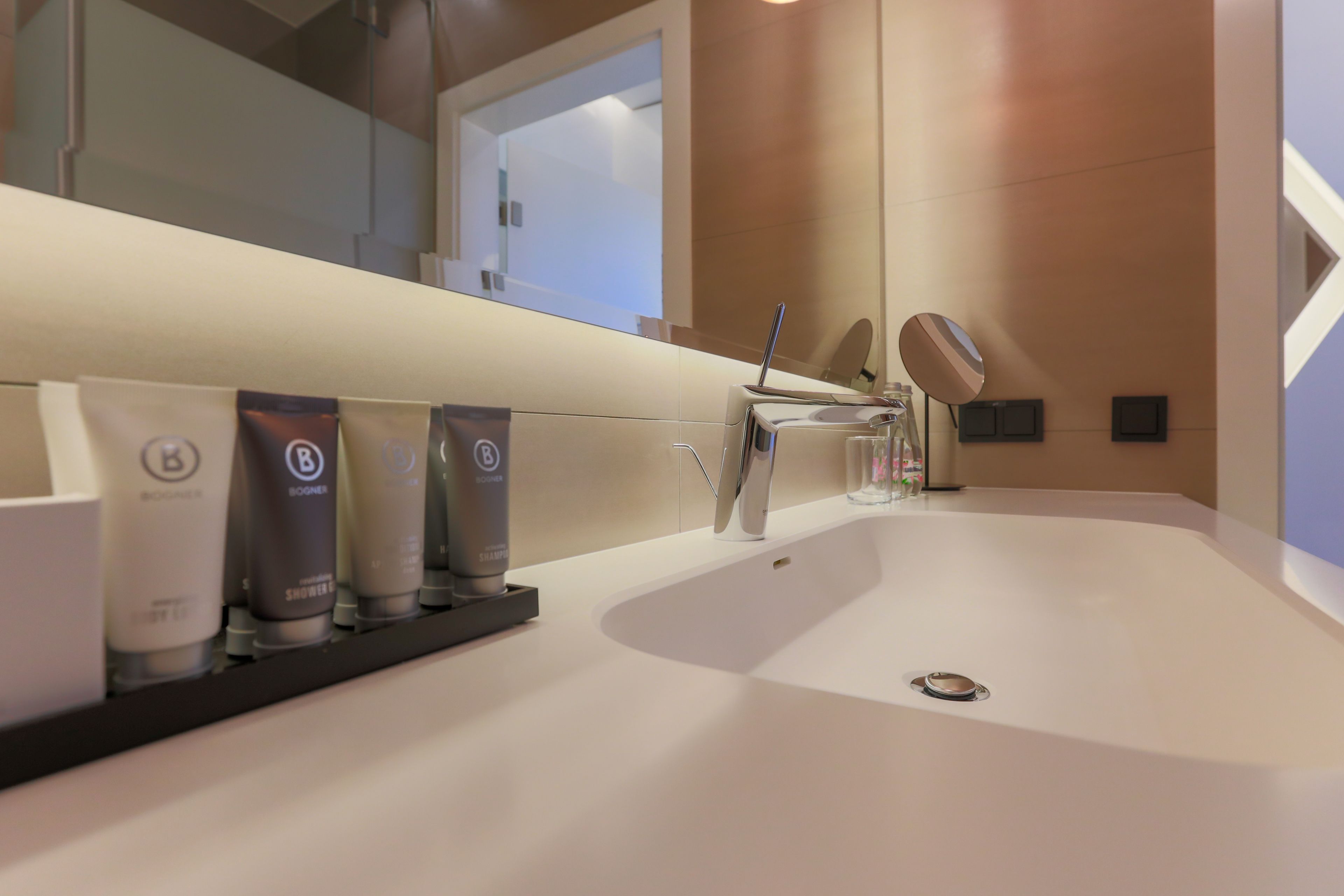 Un baño moderno con un lavabo grande, un espejo y artículos de aseo en un estante.