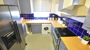 Een kleine keuken met een inbouwoven, een wasmachine en een kookplaat.