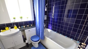 Een badkamer met een witte wastafel, een blauw toilet en een bad.