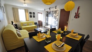 Een eetgedeelte met een tafel voor twee, kaarsen en een gitaar aan de muur.