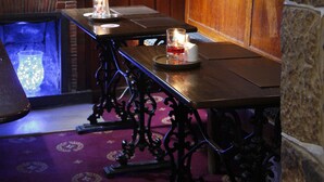 A dimly lit room with a wooden table, two candles, and a stone wall. - The Peacock Inn (Bakewell)