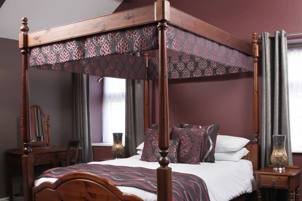 A four-poster canopy bed with a wooden frame and a patterned canopy.