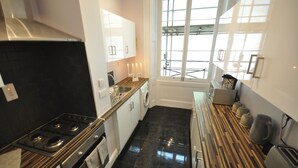 A modern kitchen with a stove, oven, and sink. There is a window with a view of the outside. - Paddington Guest Apartment (London)