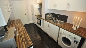 A compact kitchen with a built-in oven, a dishwasher, and a washing machine. - Paddington Guest Apartment (London)