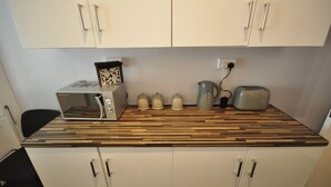 A kitchen with a wooden countertop, a microwave, a toaster, and four milk cartons. - Paddington Guest Apartment (London)
