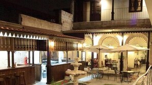 An outdoor seating area with tables and umbrellas, a bar with stools, and a staircase leading to an upper level. - Hotel Santa Rosa (Arequipa)