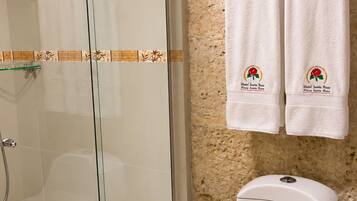 A bathroom with a glass shower enclosure, a toilet with a 'INFECTA' label, and two towels hanging on a rack with 'Hotel Santa Rosa' branding.