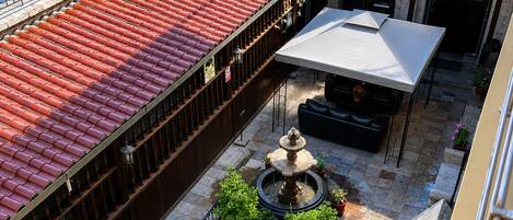 A courtyard with a fountain, seating areas, and a covered patio.