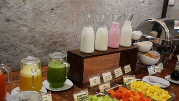 Un bufé con diversas opciones de comida y bebida, incluyendo jugos, leche y frutas.