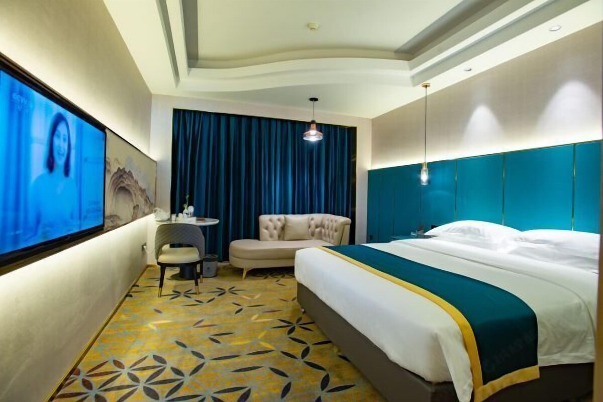 Habitación de hotel con una cama grande, una zona de estar pequeña, un televisor y un piso estampado.