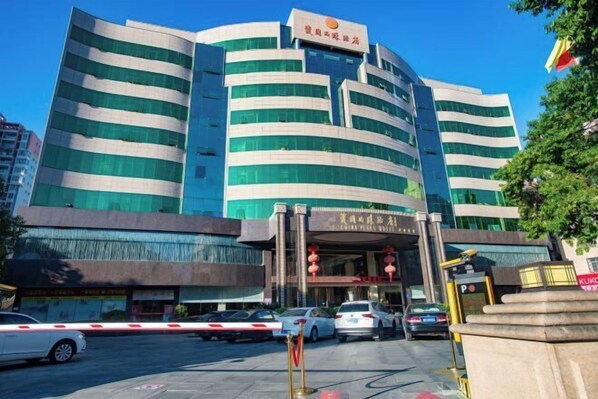 A multi-story building with a modern design, featuring a prominent entrance with a sign. - China Pearl Hotel (Dehua)