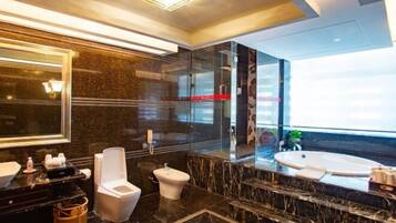 A modern bathroom with a large mirror, a bidet, a toilet, and a bathtub.