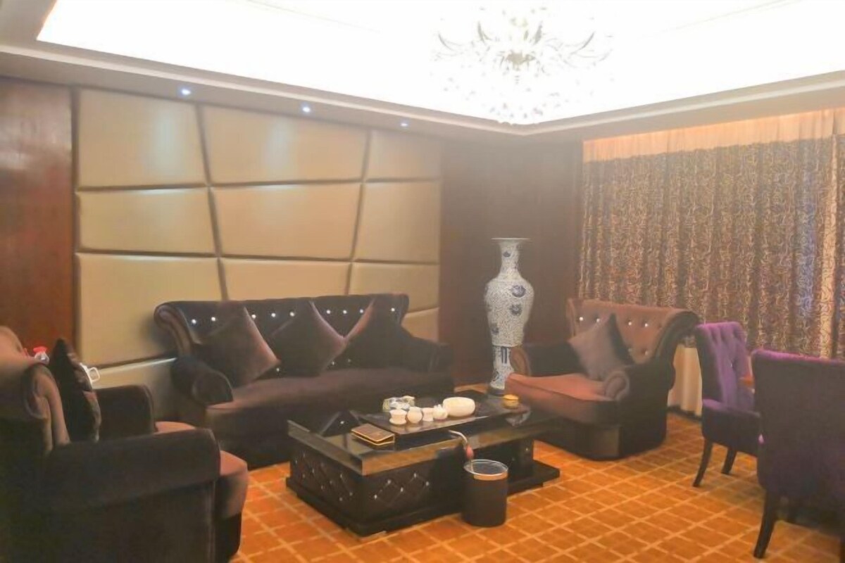 Una sala de estar con sofá, sillones, una mesa de centro y un florero.