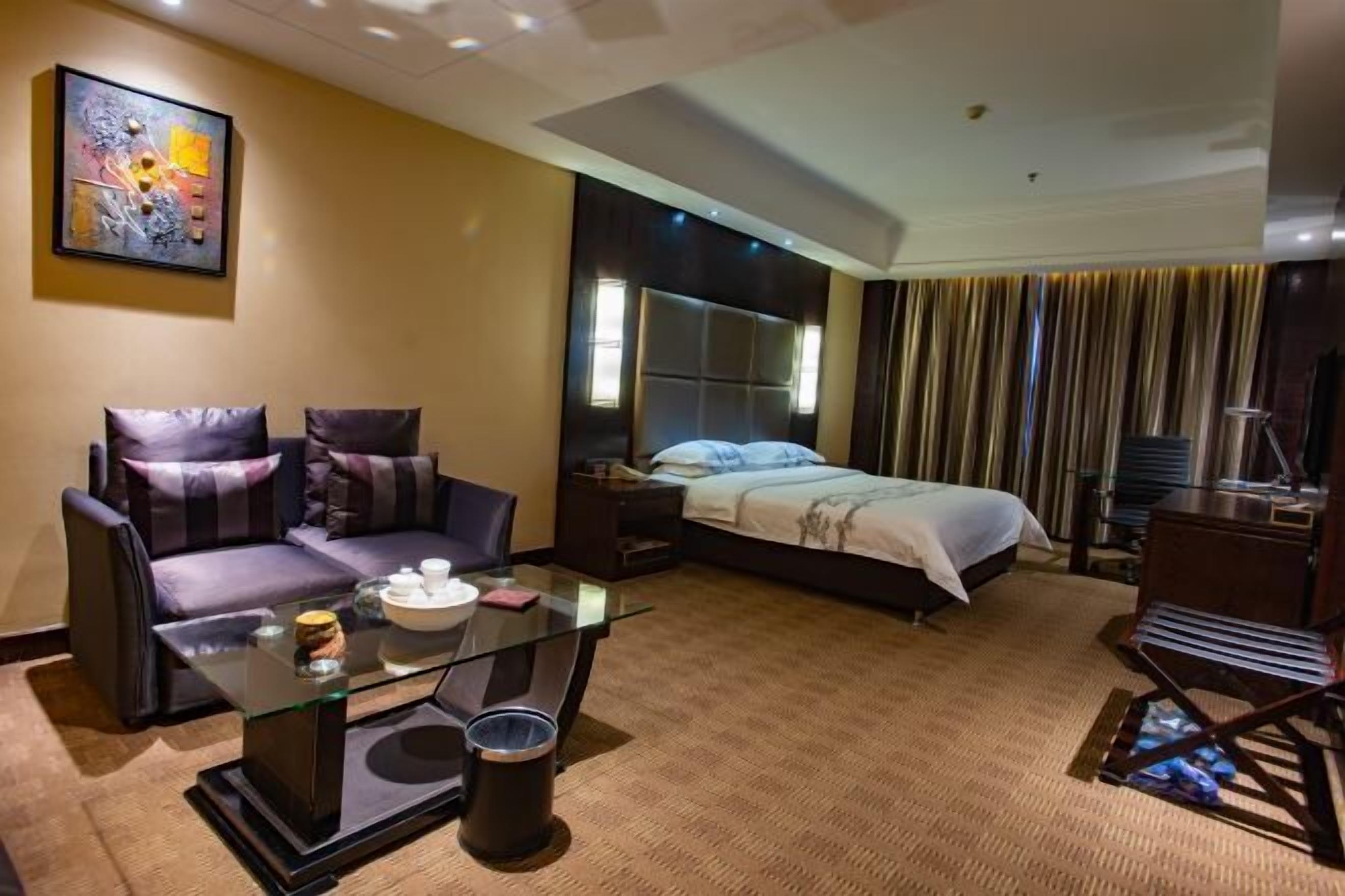Une chambre d’hôtel comprenant un lit, un canapé, une table basse en verre, un bureau et une chaise.