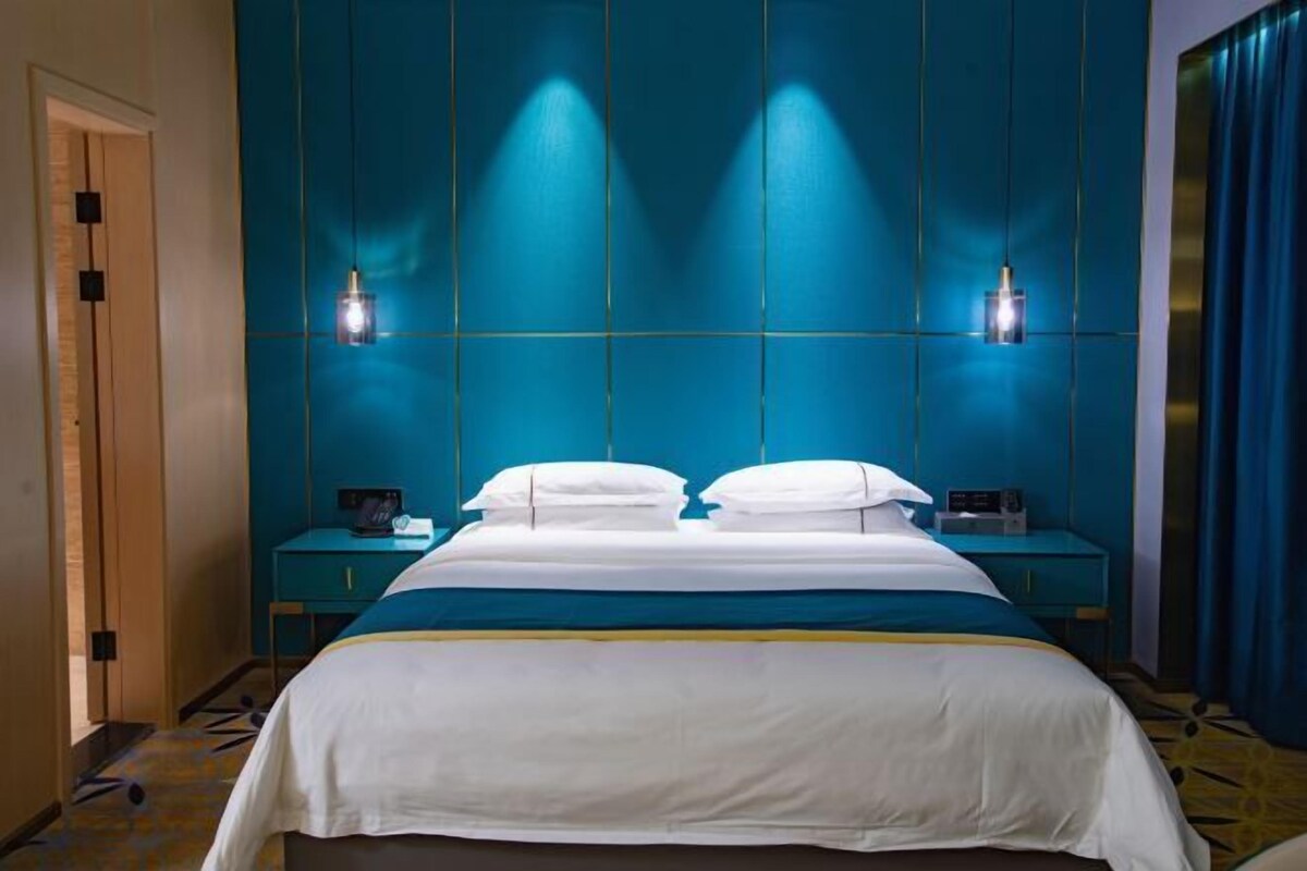 Una habitación de hotel con una cama grande, dos mesitas de noche y una pared azul decorativa.