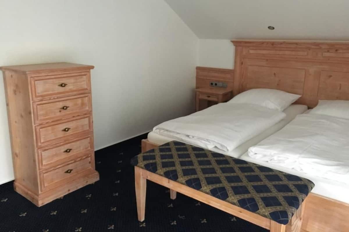 Une chambre à coucher avec un lit, une commode en bois et un banc.