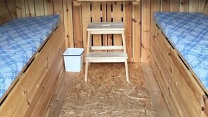Een knus blokhut met twee houten stapelbedden, een kleine houten ladder en een raam met uitzicht op de natuur.