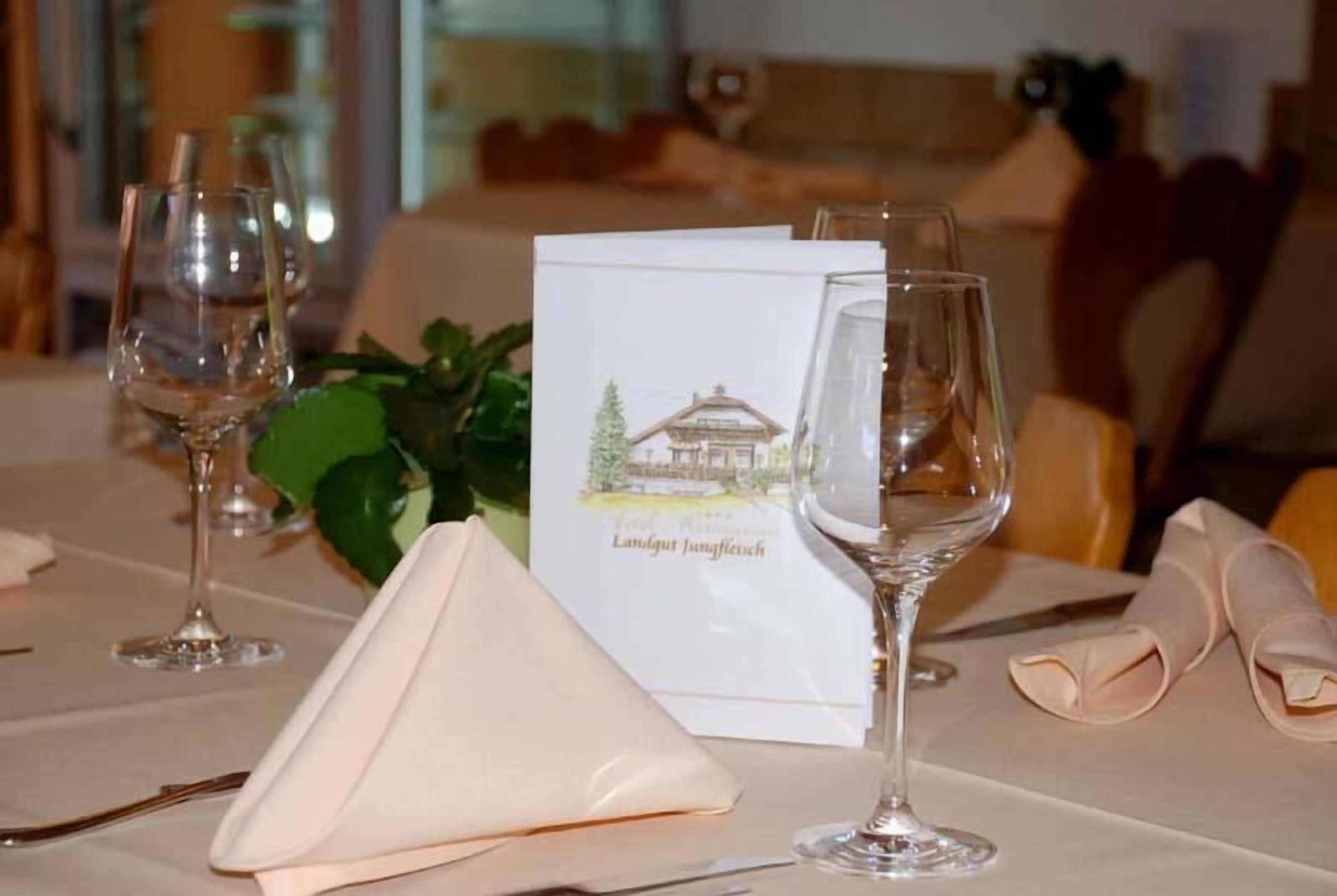 A dining table set with wine glasses, a menu, and a napkin.