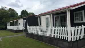 Een rij vakantiehuisjes met witte hekken en een gazon.