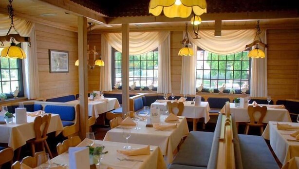 Een restaurant met houten wanden, witte tafels en blauwe zitbanken.