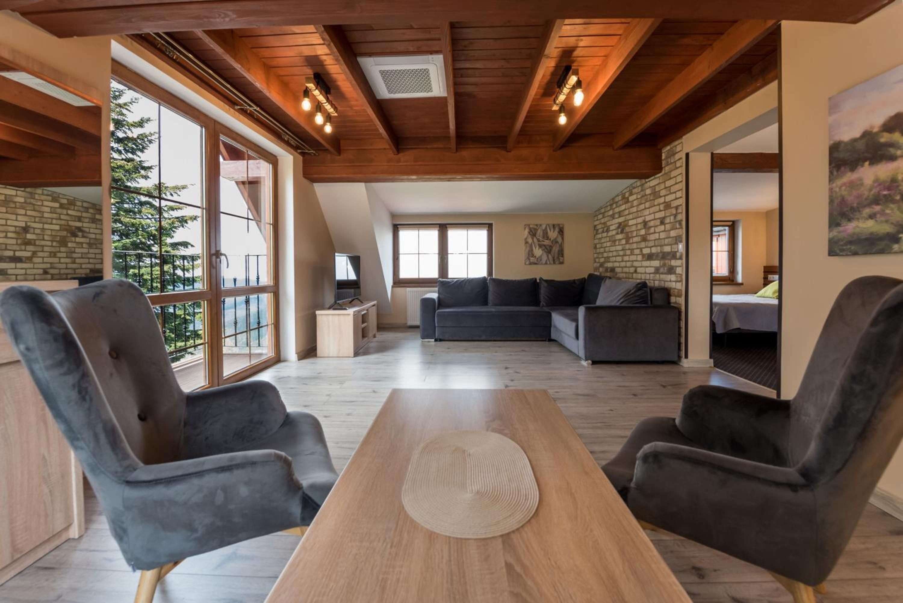 Een moderne woonkamer met een houten plafond, grote ramen en een bank.