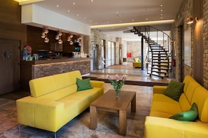 A modern interior with a yellow sofa set, a wooden coffee table, and a staircase leading to an upper level. - Hotel Beskidzki Raj Medical Spa (Stryszawa)