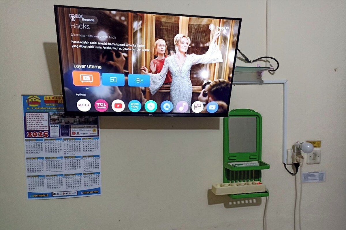 Ein an der Wand befestigter Fernseher zeigt ein Programm mit verschiedenen Symbolen darunter.