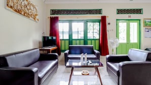 A living room with a sofa set, a coffee table, a television, and a fan. - Bahagia Sederhana Home Stay - Hostel (Bantul)