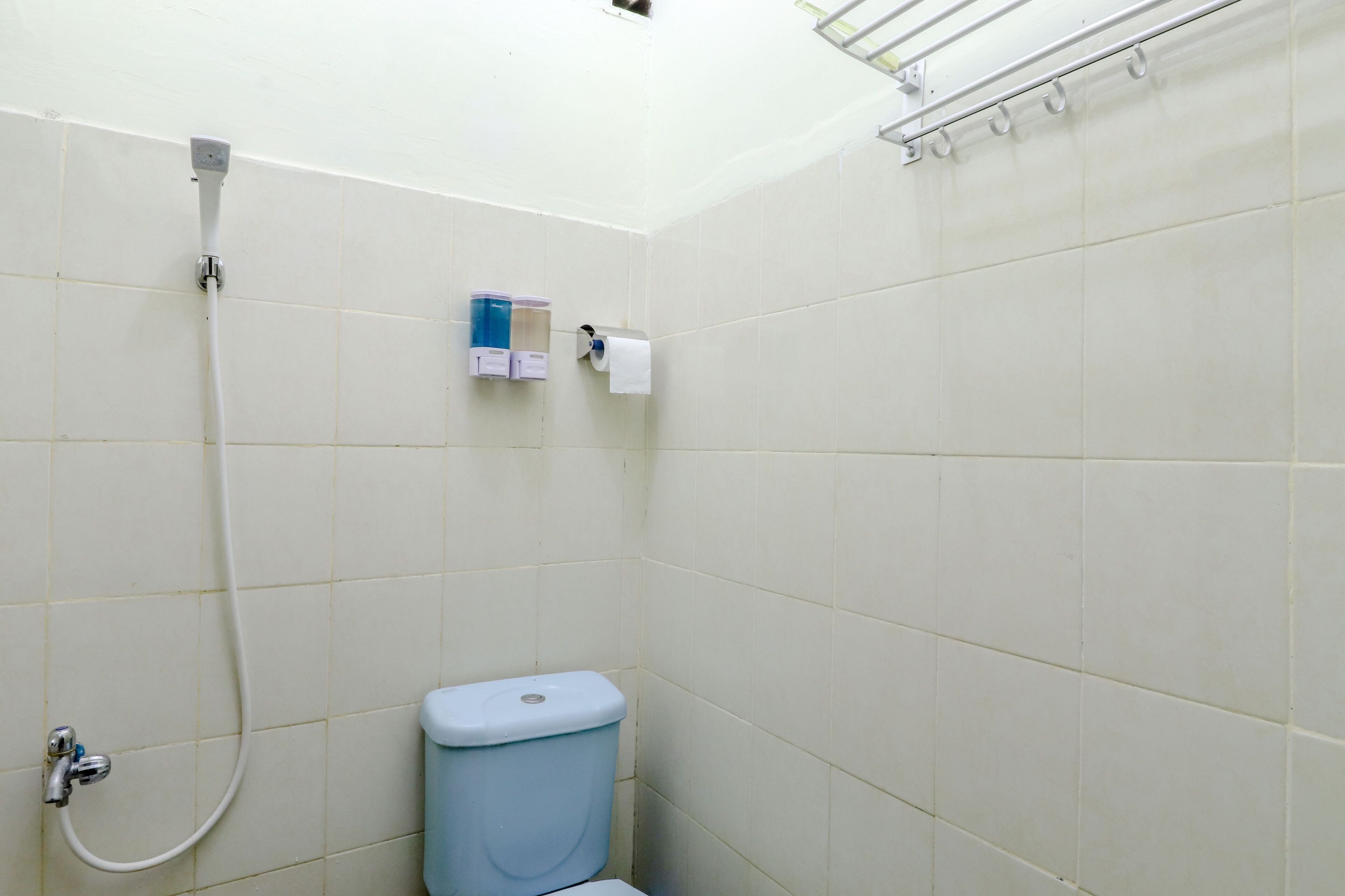 A small bathroom with a toilet, a shower, and a towel rack.
