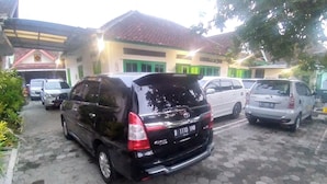A black minivan parked on a paved area with a building in the background. - Bahagia Sederhana Home Stay - Hostel (Bantul)