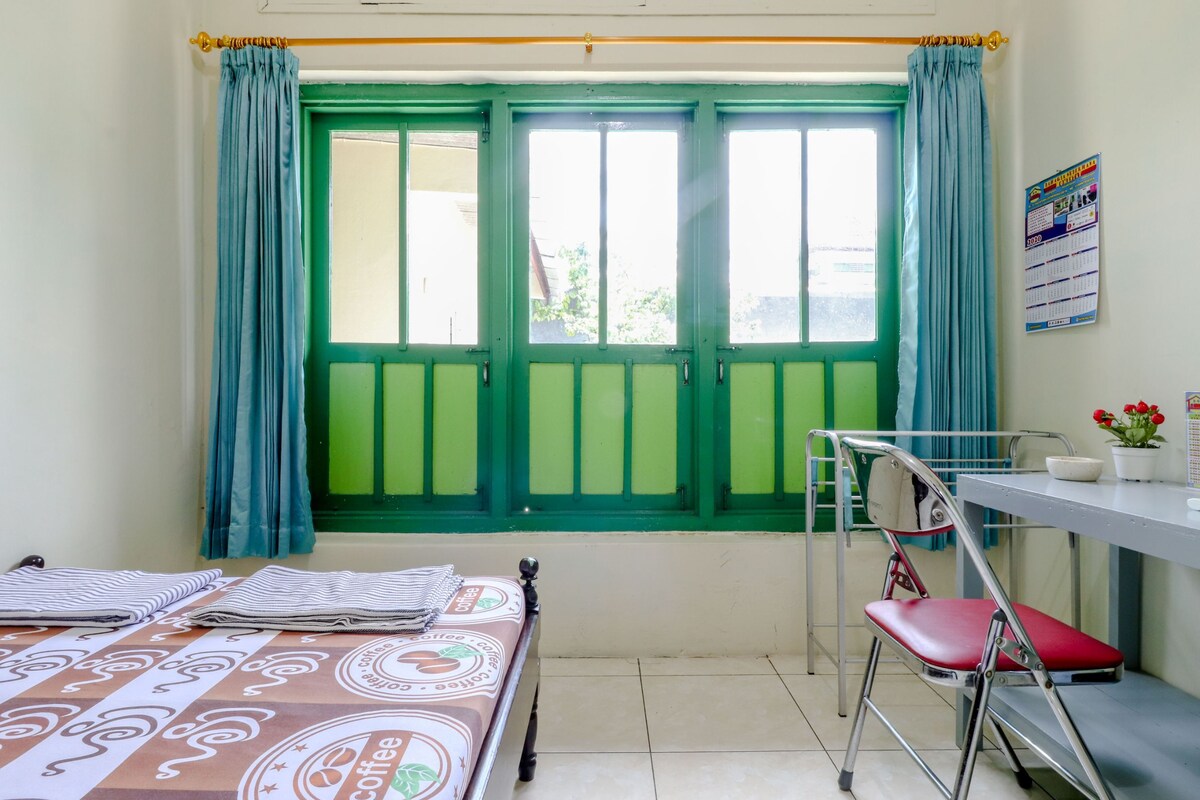 Una habitación con cama, escritorio, silla y ventana con cortinas.