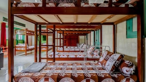 A traditional room with wooden furniture, including a sofa and a bed with patterned cushions. - Bahagia Sederhana Home Stay - Hostel (Bantul)