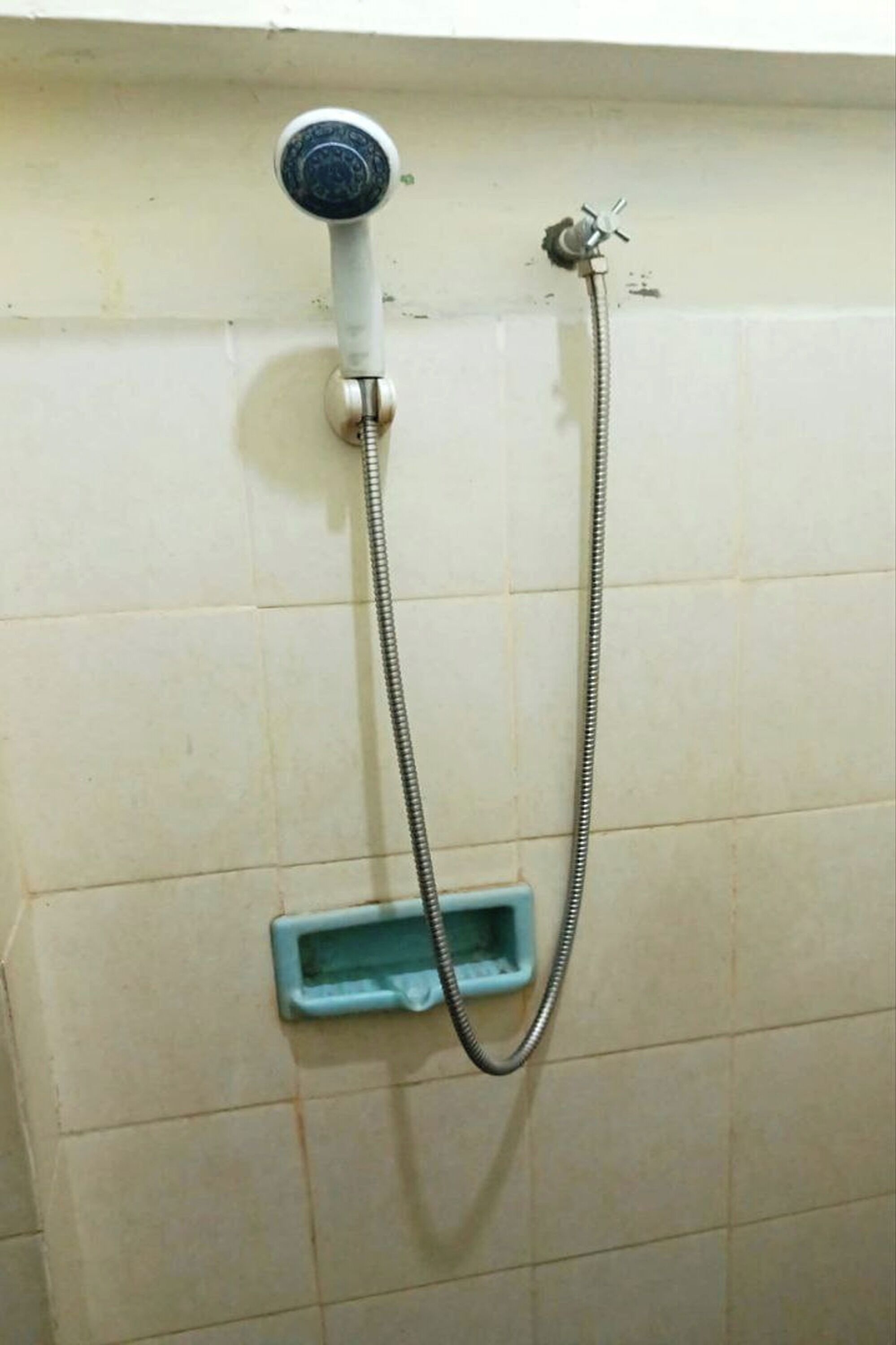 A shower with a handheld showerhead and a wall-mounted faucet.