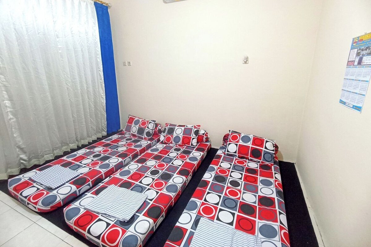 Una habitación con una cama, una cortina, un aire acondicionado y un cartel en la pared.
