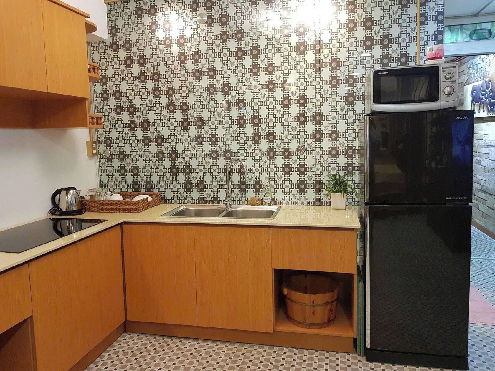 Eine kleine Küche mit Holzausstattung, einem Edelstahl-Spülbecken, einer Mikrowelle und einem Kühlschrank.