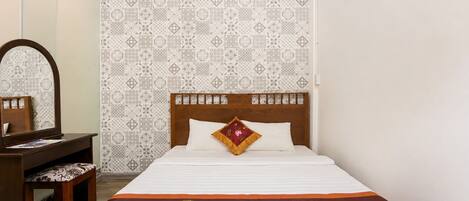 Un dormitorio con cama, mesita de noche de madera, espejo y papel tapiz estampado.