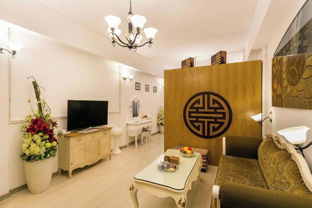 Una sala de estar moderna con un televisor de pantalla plana, un comedor y una pared decorativa con un diseño geométrico.