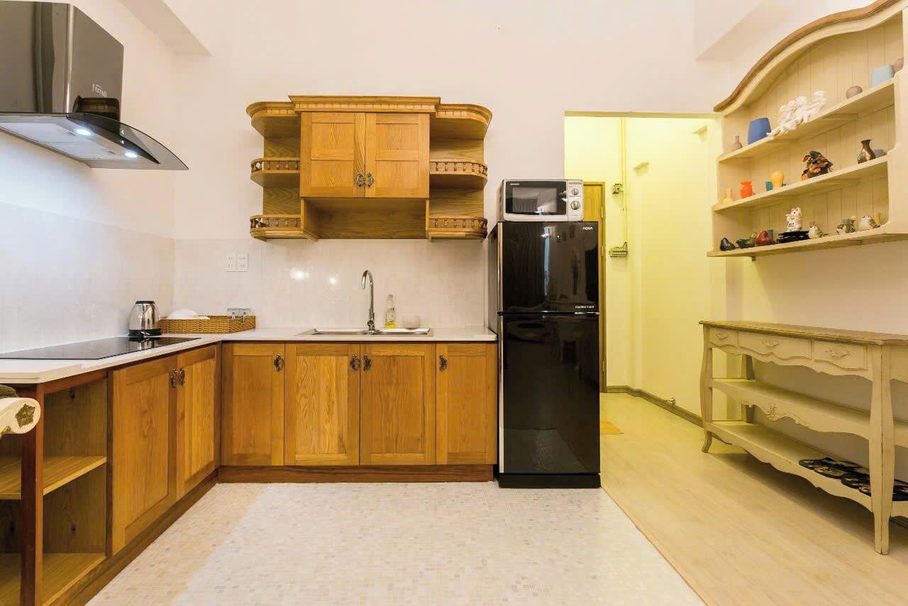 Een kleine keuken met houten kastjes, een ingebouwde magnetron en een koelkast.